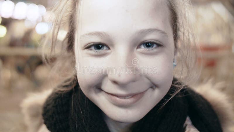 Retrato do close-up de uma menina de sorriso nova feliz que olha a câmera Menina bonita na rua, a luz nela