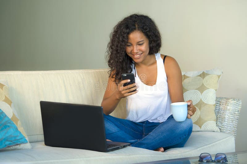 Retrato do estilo de vida da mulher afro-americana preta feliz e bonita nova que usa o Internet que texting no telefone celular a imagens de stock Retrato do estilo de vida da mulher afro-americana preta feliz e bonita nova que usa o Internet que texting no telefone celular a imagens de stock