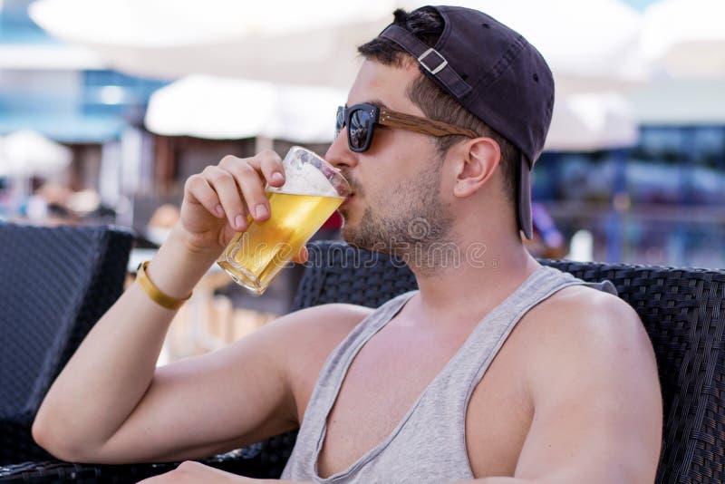 Retrato do homem considerável novo que bebe a cerveja de refrescamento fria imagem de stock royalty free Retrato do homem considerável novo que bebe a cerveja de refrescamento fria imagem de stock royalty free