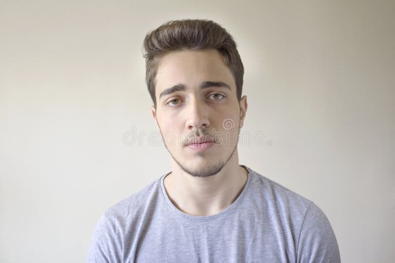 Retrato do homem considerável novo que olha a câmera isolada no fundo cinzento imagens de stock Retrato do homem considerável novo que olha a câmera isolada no fundo cinzento imagens de stock