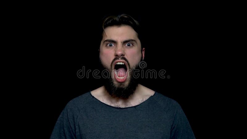 Retrato do homem considerável do rugido com a barba que está e que grita com a boca aberta grande, isolado no fundo preto novo foto de stock royalty free Retrato do homem considerável do rugido com a barba que está e que grita com a boca aberta grande, isolado no fundo preto novo foto de stock royalty free