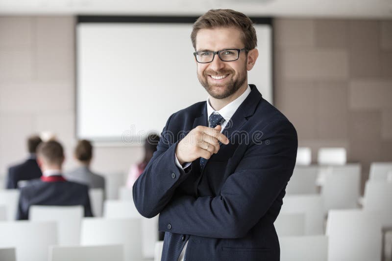 Retrato do homem de negócios feliz que está no salão do seminário