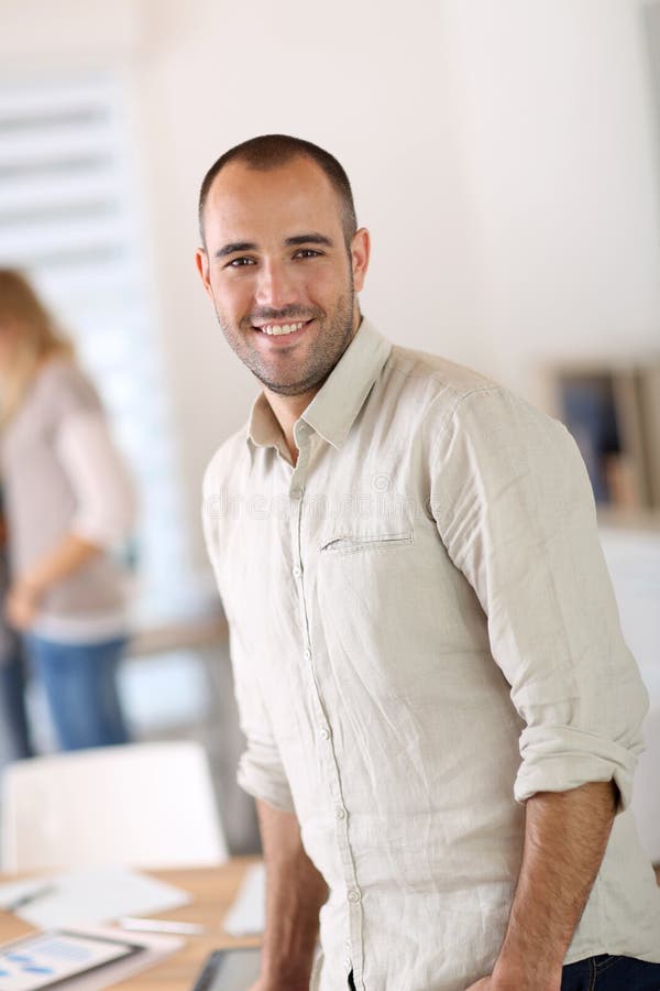 Retrato do homem de negócios novo na posição do escritório imagens de stock royalty free Retrato do homem de negócios novo na posição do escritório imagens de stock royalty free