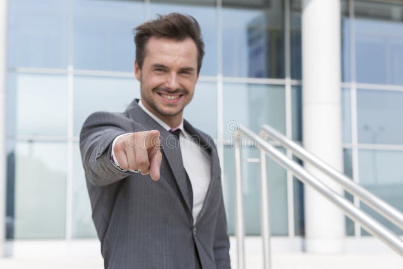 Retrato do homem de negócios seguro que aponta em você o prédio de escritórios da parte externa fotografia de stock royalty free Retrato do homem de negócios seguro que aponta em você o prédio de escritórios da parte externa fotografia de stock royalty free