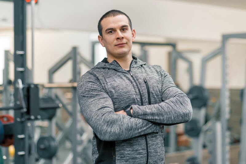 Retrato do homem desportivo muscular com mãos dobradas no gym, instrutor considerável que olha a câmera imagens de stock royalty free Retrato do homem desportivo muscular com mãos dobradas no gym, instrutor considerável que olha a câmera imagens de stock royalty free