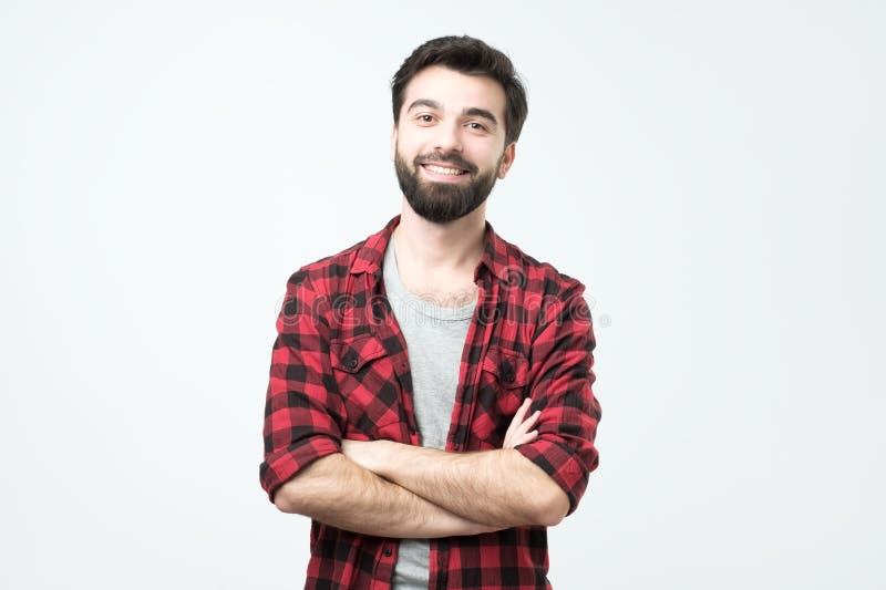Retrato do homem latino-americano considerável de sorriso na posição quadriculado da camisa com braços cruzados fotografia de stock Retrato do homem latino-americano considerável de sorriso na posição quadriculado da camisa com braços cruzados fotografia de stock