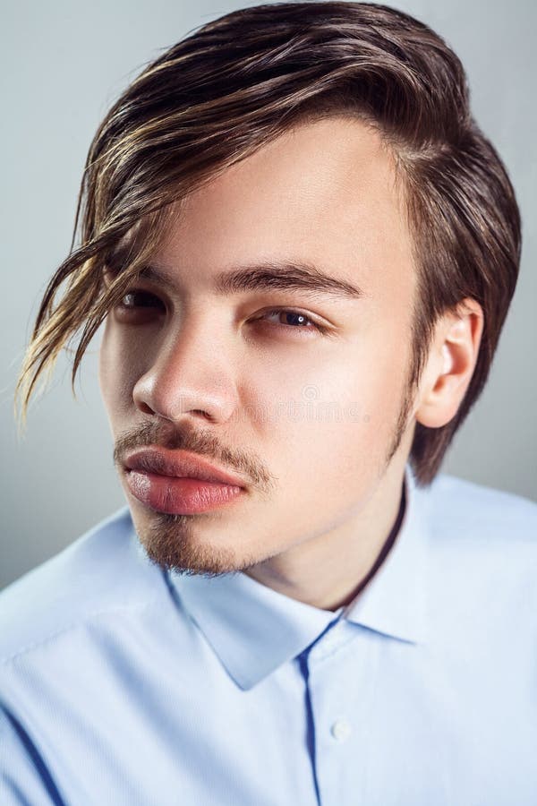 Retrato do homem novo com penteado longo da franja em seus olhos foto de stock royalty free Retrato do homem novo com penteado longo da franja em seus olhos foto de stock royalty free