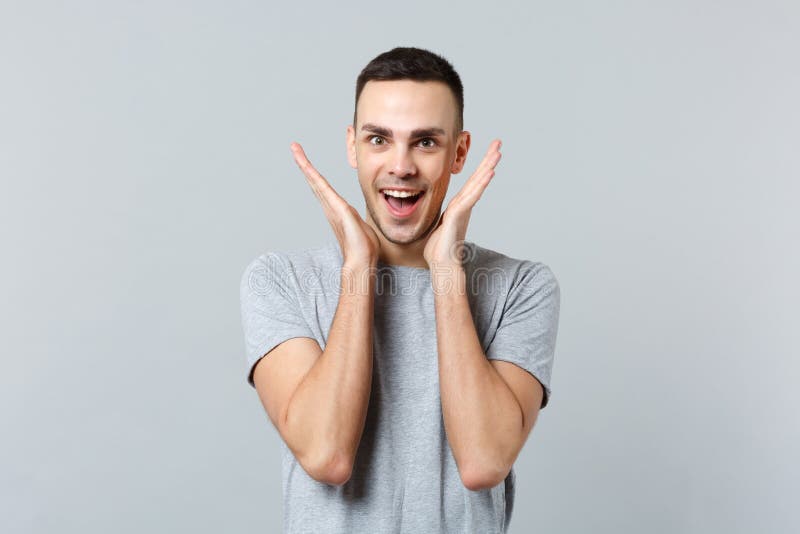 Retrato do homem novo entusiasmado na roupa ocasional que mantém a boca mãos abertas, espalhando perto da cara isolada no cinza fotografia de stock Retrato do homem novo entusiasmado na roupa ocasional que mantém a boca mãos abertas, espalhando perto da cara isolada no cinza fotografia de stock