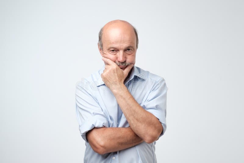 Retrato do homem sério idoso que fricciona seu queixo fotos de stock Retrato do homem sério idoso que fricciona seu queixo fotos de stock