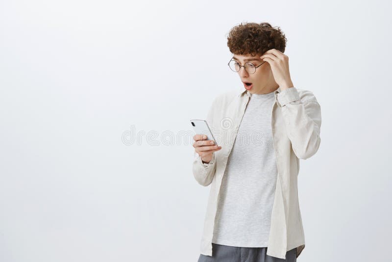 Retrato do homem à moda bonito chocado e impresso com penteado encaracolado nos vidros redondos que deixam cair a maxila como a l foto de stock Retrato do homem à moda bonito chocado e impresso com penteado encaracolado nos vidros redondos que deixam cair a maxila como a l foto de stock