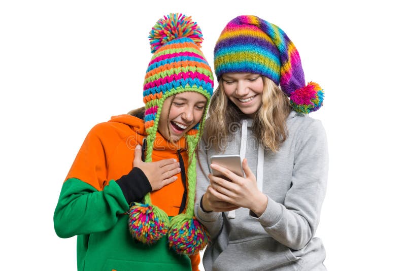 Retrato do inverno de duas amigas adolescentes bonitas felizes nos chapéus feitos malha que têm o divertimento com telefone celul fotos de stock royalty free Retrato do inverno de duas amigas adolescentes bonitas felizes nos chapéus feitos malha que têm o divertimento com telefone celul fotos de stock royalty free