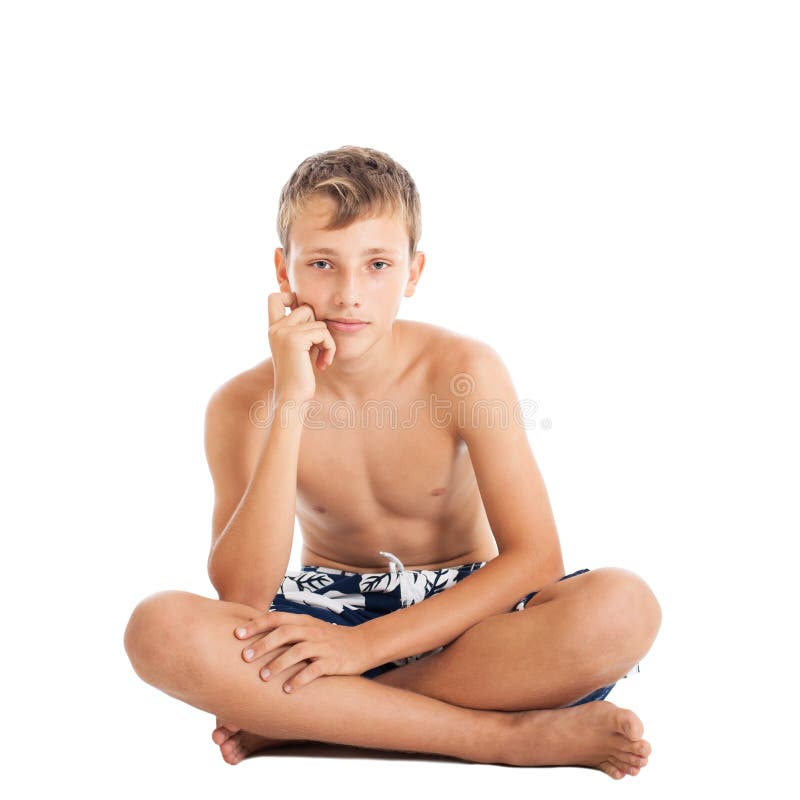 Retrato do short vestindo de uma natação do menino adolescente europeu bonito. Um menino que senta-se no assoalho. fotografia de stock Retrato do short vestindo de uma natação do menino adolescente europeu bonito. Um menino que senta-se no assoalho. fotografia de stock