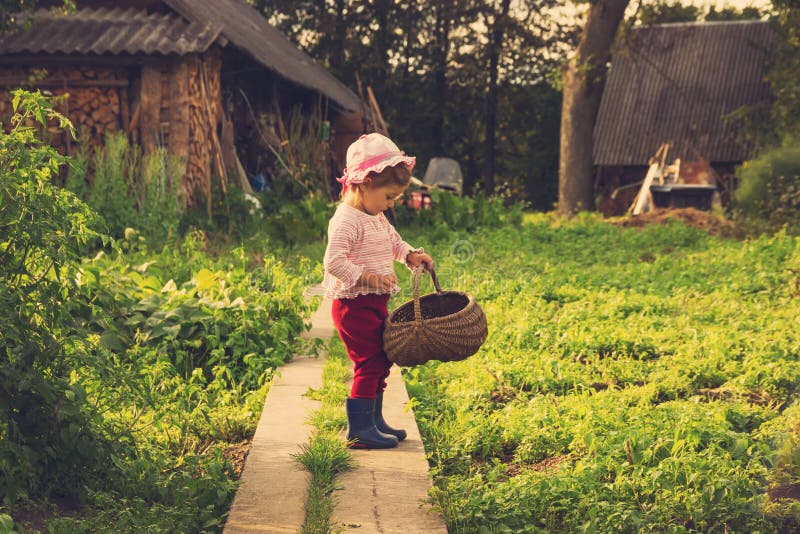 Retrato do vintage da criança bonito feliz com a cesta grande que tem o divertimento no campo foto de stock Retrato do vintage da criança bonito feliz com a cesta grande que tem o divertimento no campo foto de stock