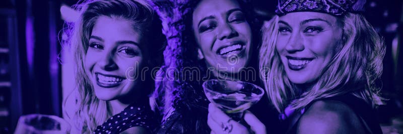 Retrato dos amigos fêmeas que guardam bebidas no clube fotografia de stock Retrato dos amigos fêmeas que guardam bebidas no clube fotografia de stock