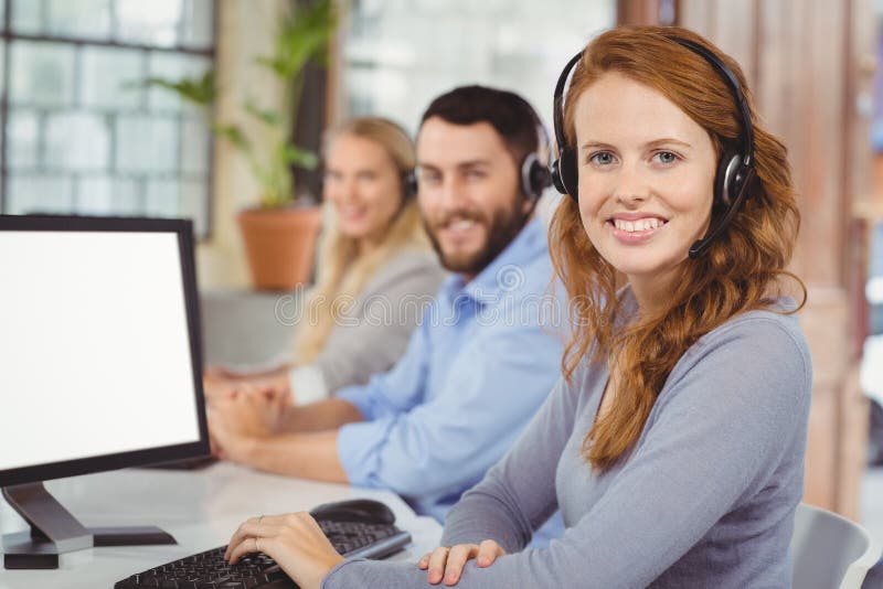 Retrato dos operadores de sorriso que trabalham no escritório imagem de stock Retrato dos operadores de sorriso que trabalham no escritório imagem de stock