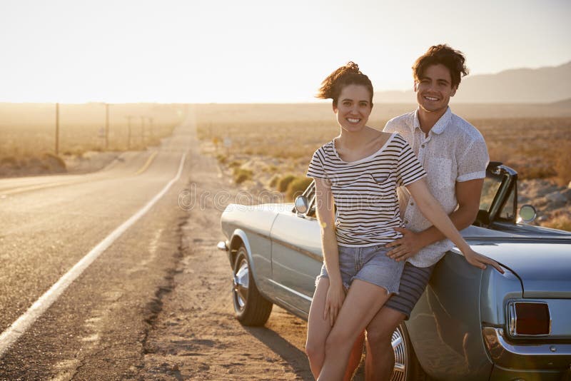 Retrato dos pares românticos que apreciam a viagem por estrada no carro clássico foto de stock Retrato dos pares românticos que apreciam a viagem por estrada no carro clássico foto de stock