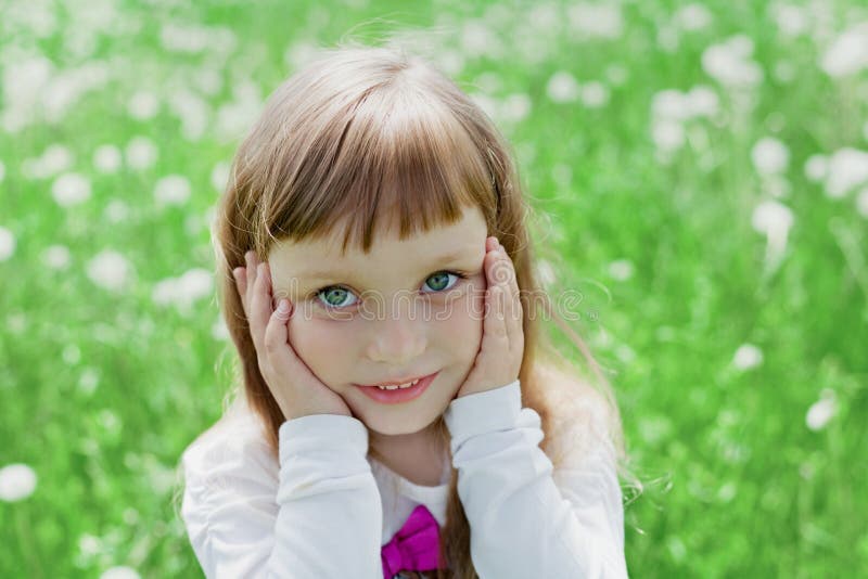 Retrato emocional del primer de la niña linda con los ojos conmovedores hermosos que se colocan en un prado verde fotos de archivo libres de regalías Retrato emocional del primer de la niña linda con los ojos conmovedores hermosos que se colocan en un prado verde fotos de archivo libres de regalías