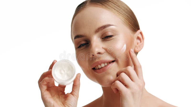 Retrato en cámara lenta mujer joven usa cremas de su cara. concepto para piel fresca hidratada hermosa cara cosmética de closeup almacen de video