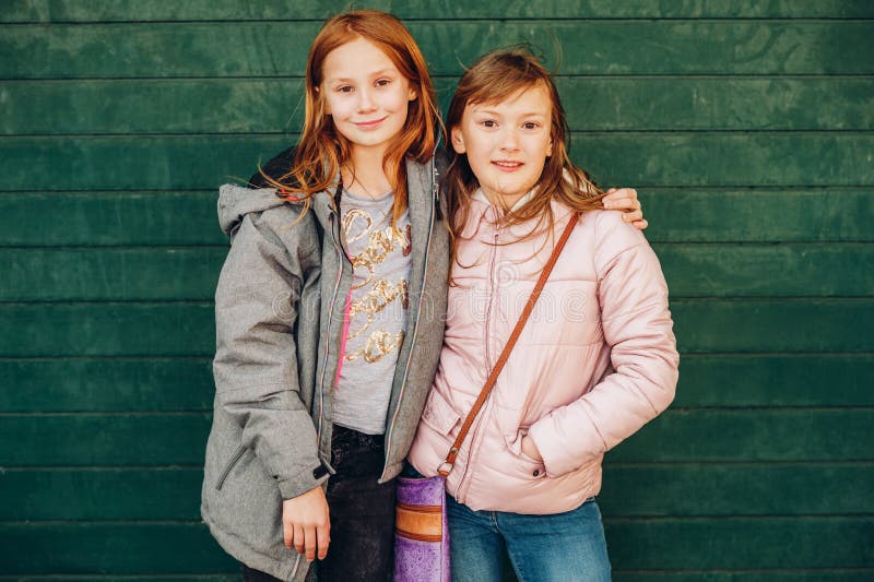 Retrato exterior de duas meninas adolescentes pequenas bonitos que vestem revestimentos mornos imagens de stock Retrato exterior de duas meninas adolescentes pequenas bonitos que vestem revestimentos mornos imagens de stock