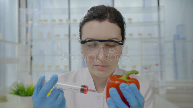 Retrato feminino cientista dá injeção com seringa com líquido para tomate em laboratório moderno