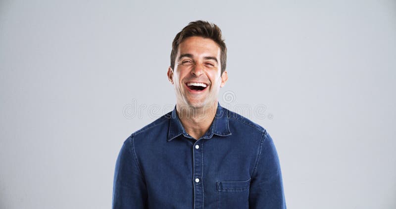 Retrato gracioso y hombre con humor en estudio y riéndose con mentalidad positiva en el espacio de fondo gris. Persona feliz imagenes de archivo