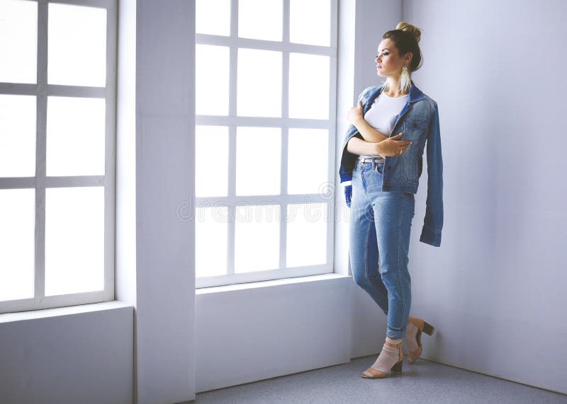 Retrato hermoso de la mujer que coloca la ventana cercana En el fondo blanco fotografía de archivo Retrato hermoso de la mujer que coloca la ventana cercana En el fondo blanco fotografía de archivo