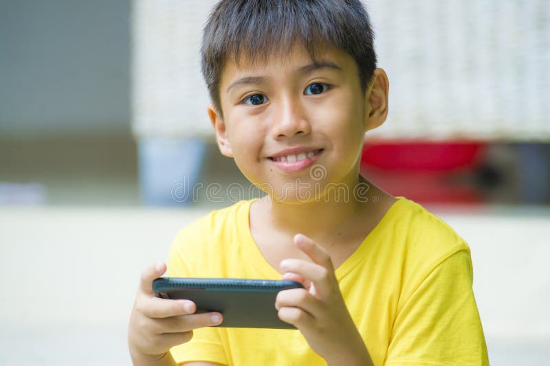 Retrato isolado do estilo de vida de 7 ou 8 anos de criança asiática idosa que joga com o jardim do ar livre do telefone celular fotos de stock royalty free Retrato isolado do estilo de vida de 7 ou 8 anos de criança asiática idosa que joga com o jardim do ar livre do telefone celular fotos de stock royalty free