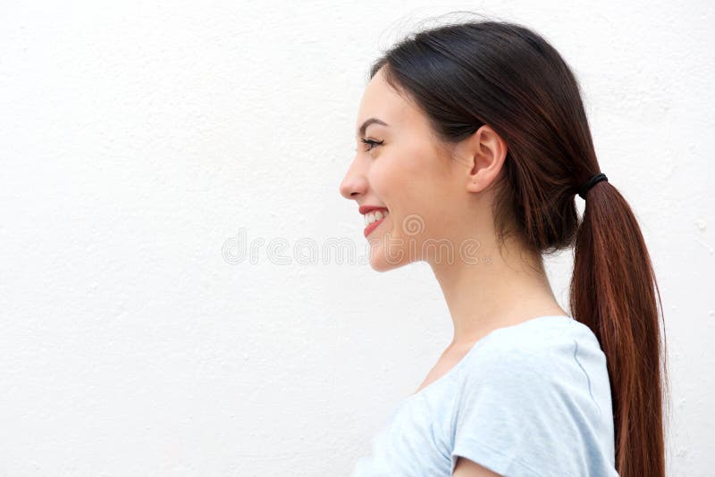 Retrato lateral da jovem mulher saudável com sorriso longo do cabelo
