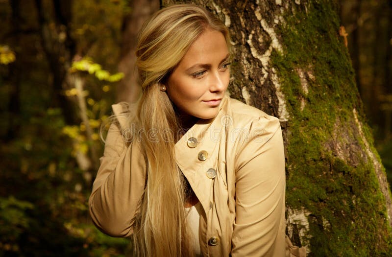 Retrato louro bonito da mulher na floresta com fundo verde e amarelo das árvores imagem de stock Retrato louro bonito da mulher na floresta com fundo verde e amarelo das árvores imagem de stock