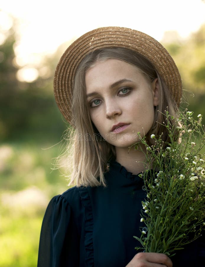 Retrato natural de uma menina em um chapéu de palha com um ramalhete de selvagem imagem de stock Retrato natural de uma menina em um chapéu de palha com um ramalhete de selvagem imagem de stock