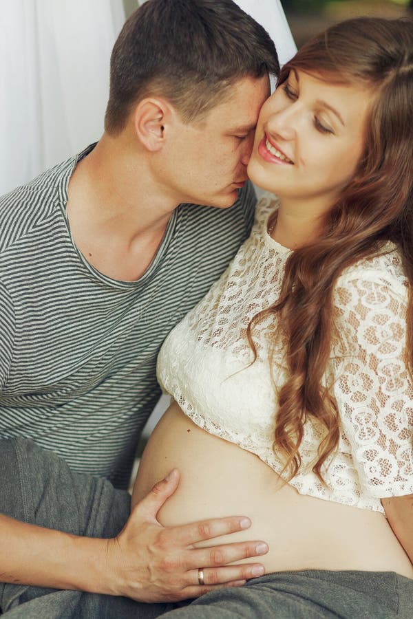 Retrato novo dos pares da família, marido e beijo grávido da esposa imagens de stock Retrato novo dos pares da família, marido e beijo grávido da esposa imagens de stock