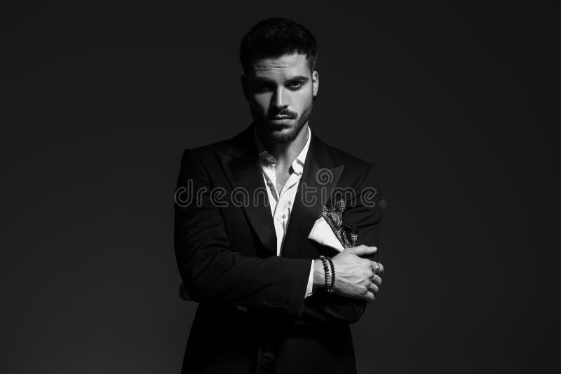 Black and white portrait of a sexy young man in tuxedo standing with hands crossed. Black and white portrait of a sexy young man in tuxedo standing with hands crossed