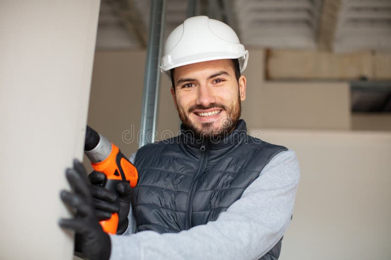 Retrato sonriente del constructor masculino usando taladro inalámbrico fotografía de archivo libre de regalías