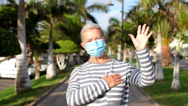Retrato y cierre de una mujer madura mirando a la cámara sonriendo y usando una máscara médica y quirúrgica para prevenir el covi metrajes