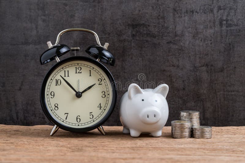 Retro alarm clock with white piggy bank and stack of coins on wooden table and black background as long term savining money or re stock photography Retro alarm clock with white piggy bank and stack of coins on wooden table and black background as long term savining money or re stock photography