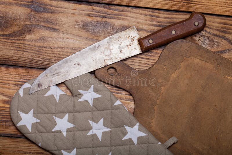 Retro cutting board, pot holder and knife on old wooden burned t