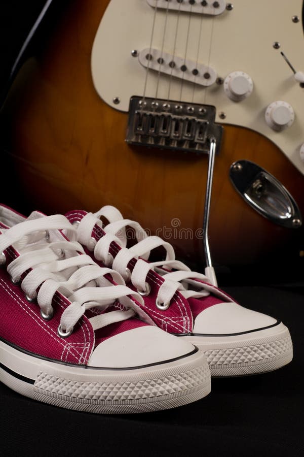 Retro Czerwoni sneakers i zamazana gitara w tle obraz royalty free Retro Czerwoni sneakers i zamazana gitara w tle obraz royalty free