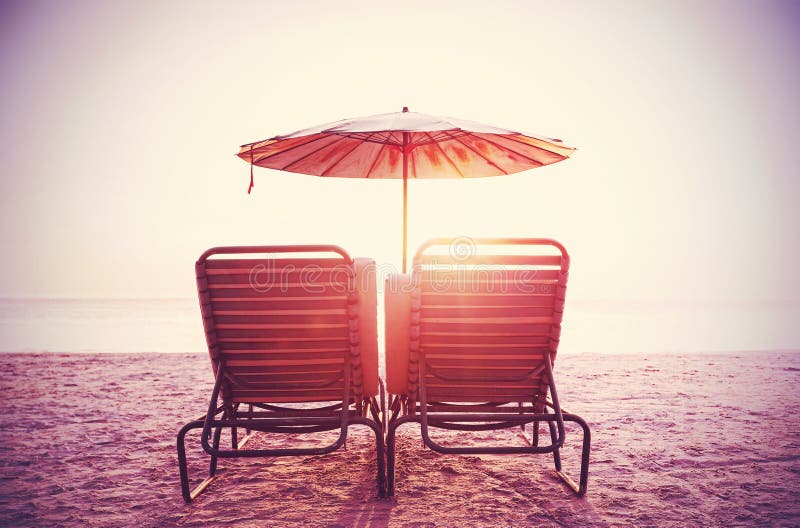 Retro- gefiltertes Bild von Strandstühlen und -regenschirm auf Sand