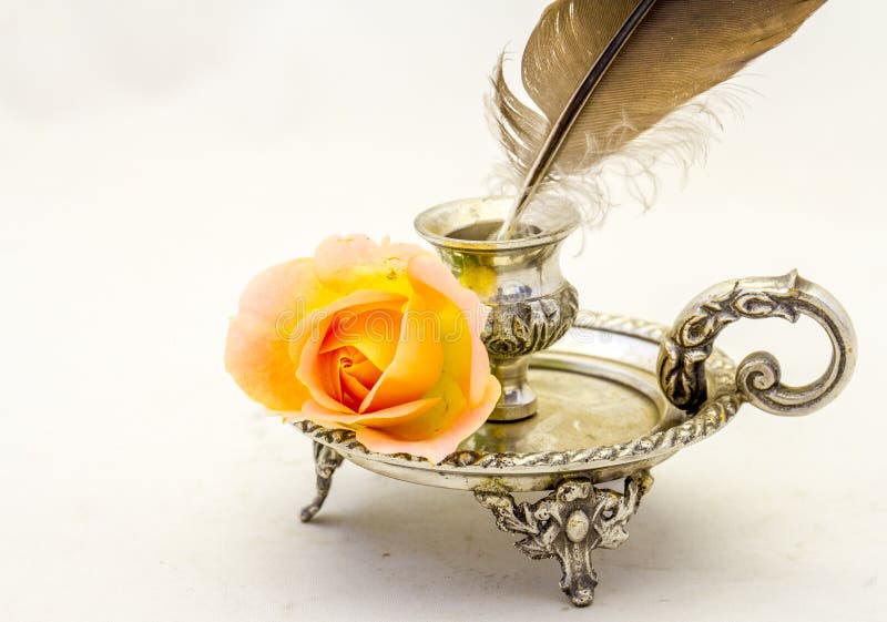 Retro inkwell feather writing pen and an orange rose stock image Retro inkwell feather writing pen and an orange rose stock image