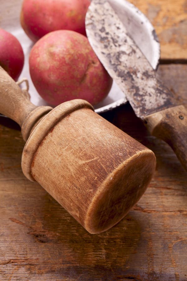 Retro- Kartoffelstampfer und -messer auf alter hölzerner Tabelle stockfotografie