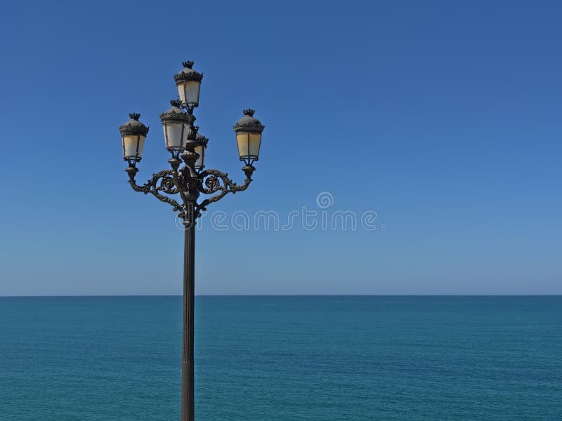 Retro lanterne della via davanti ad un mare e ad un cielo blu profondi fotografie stock libere da diritti Retro lanterne della via davanti ad un mare e ad un cielo blu profondi fotografie stock libere da diritti
