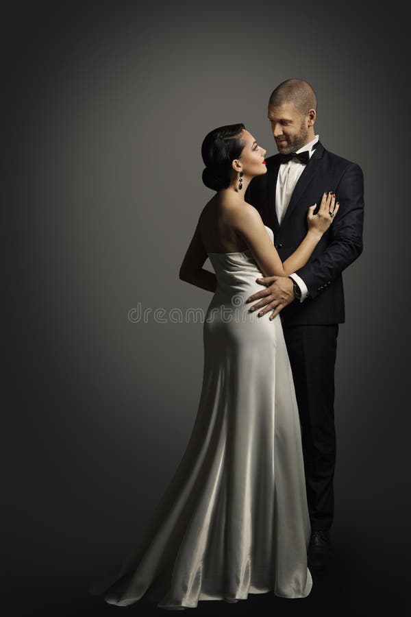 Retro Couple Portrait, Well Dressed Man in Black Suit Dancing with Woman in Long White Dress, in studio over black portrait. Retro Couple Portrait, Well Dressed Man in Black Suit Dancing with Woman in Long White Dress, in studio over black portrait