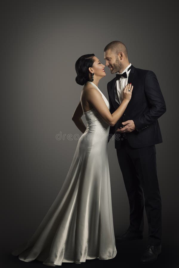 Retro Couple, Well Dressed Woman in Long White Dress and Elegant Man in Black Suit, Full Length Portrait, Studio portrait over black background. Retro Couple, Well Dressed Woman in Long White Dress and Elegant Man in Black Suit, Full Length Portrait, Studio portrait over black background
