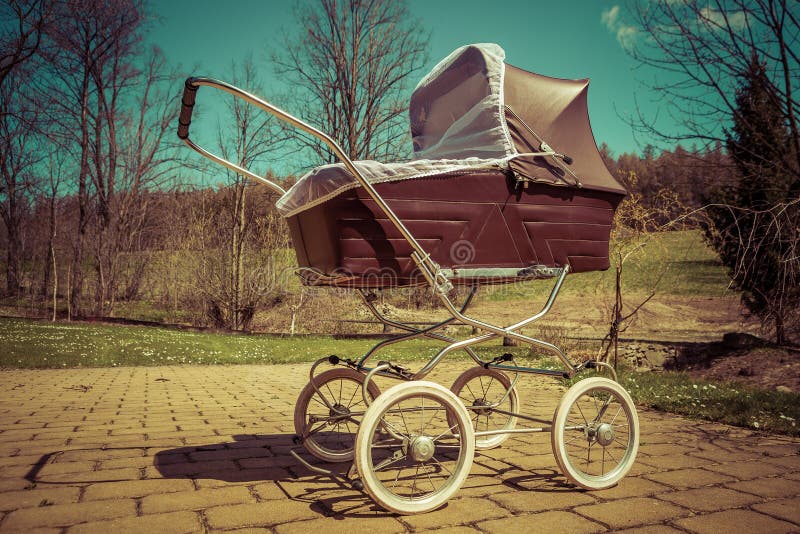 Retro style stroller baby carriage outdoors in nature on sunny day with retro vintage green instagram like filter. Retro style stroller baby carriage outdoors in nature on sunny day with retro vintage green instagram like filter