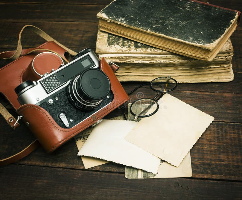 Retro still camera and some old photos on wooden table background