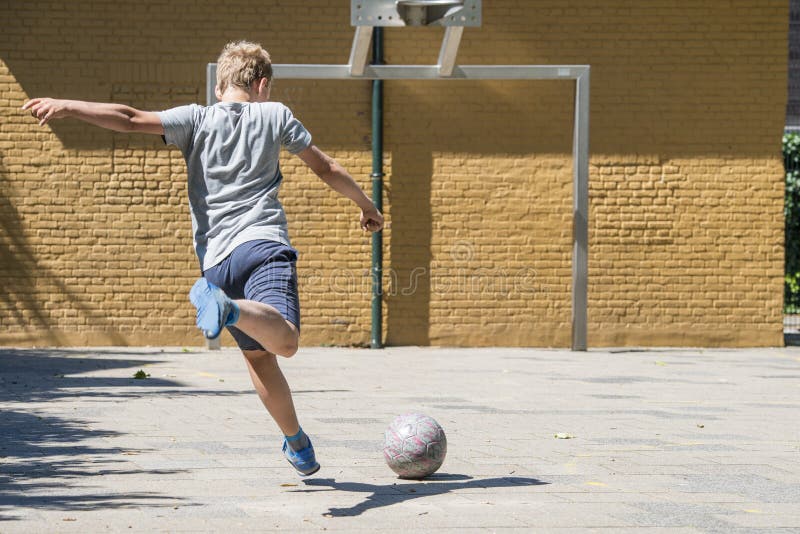 Kicking a ball towards goal on a street soccer pitch. Kicking a ball towards goal on a street soccer pitch