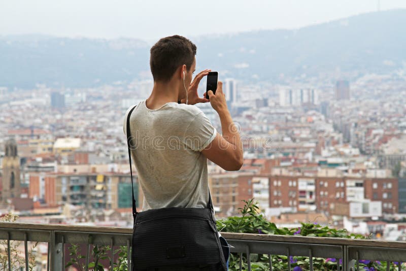 Retrovisione dell'uomo che fotografa vista di Barcellona su un telefono cellulare fotografia stock Retrovisione dell'uomo che fotografa vista di Barcellona su un telefono cellulare fotografia stock