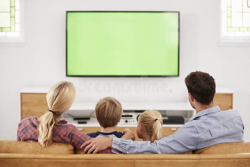 Retrovisione della famiglia che si siede su Sofa In Lounge Watching Televisio