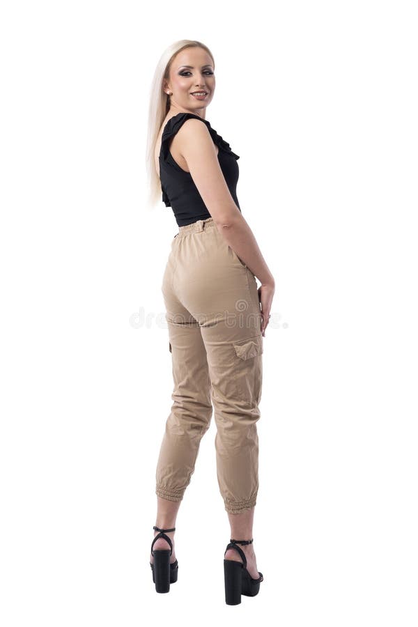 Retrovisione di giovane donna bionda sorridente sicura che gira e che esamina macchina fotografica fotografia stock Retrovisione di giovane donna bionda sorridente sicura che gira e che esamina macchina fotografica fotografia stock