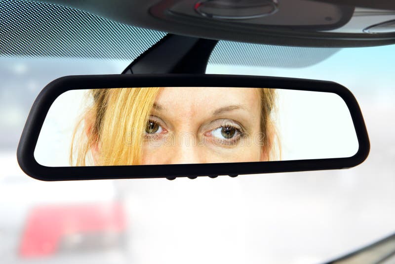 Woman sits on driver's seat and Looks in the rear-view mirror. Woman sits on driver's seat and Looks in the rear-view mirror